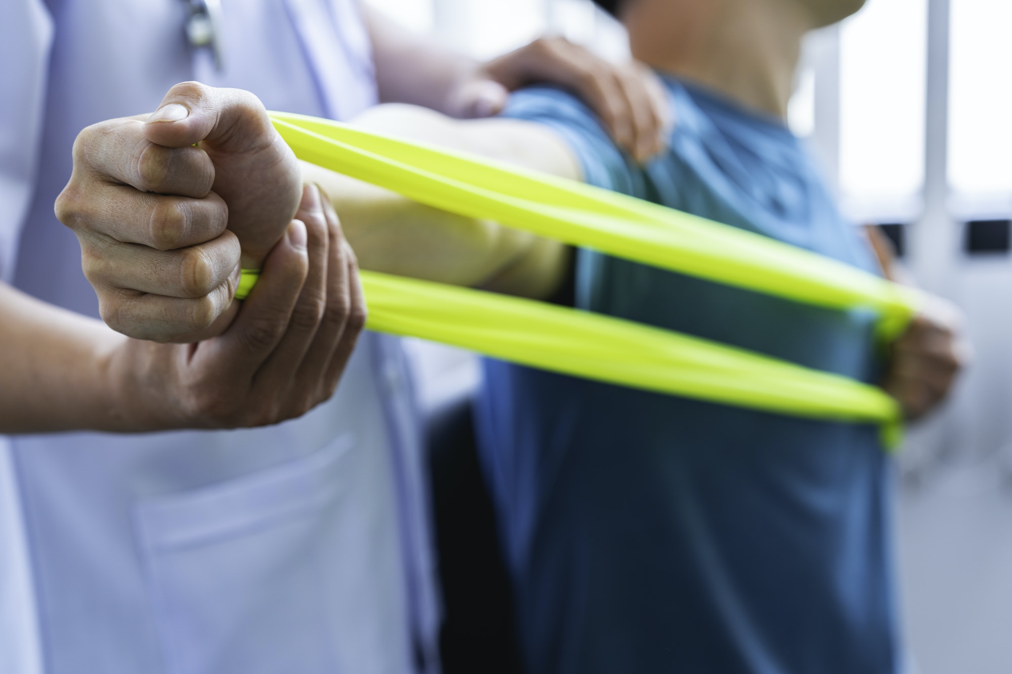 Physical therapist gives resistance band exercises. About the arms and shoulders of male office work